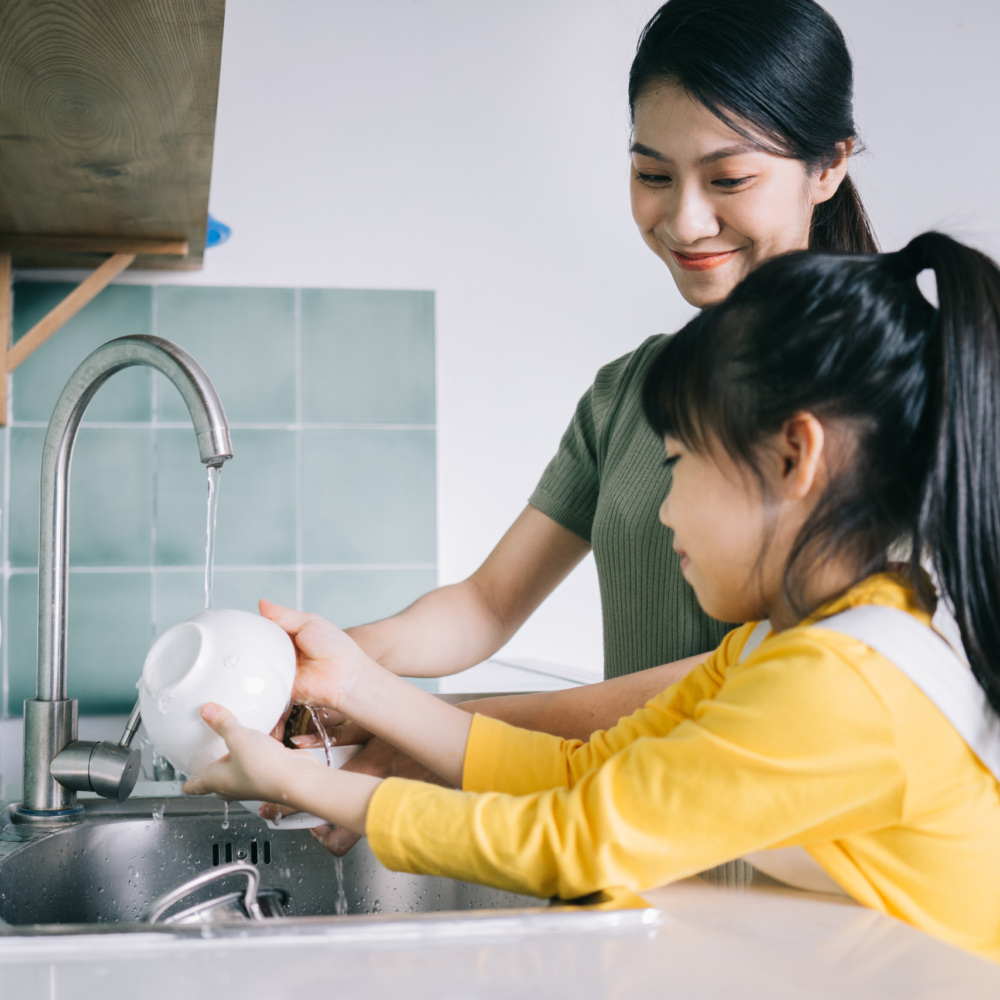 Mother and daughter wash the dishes together.